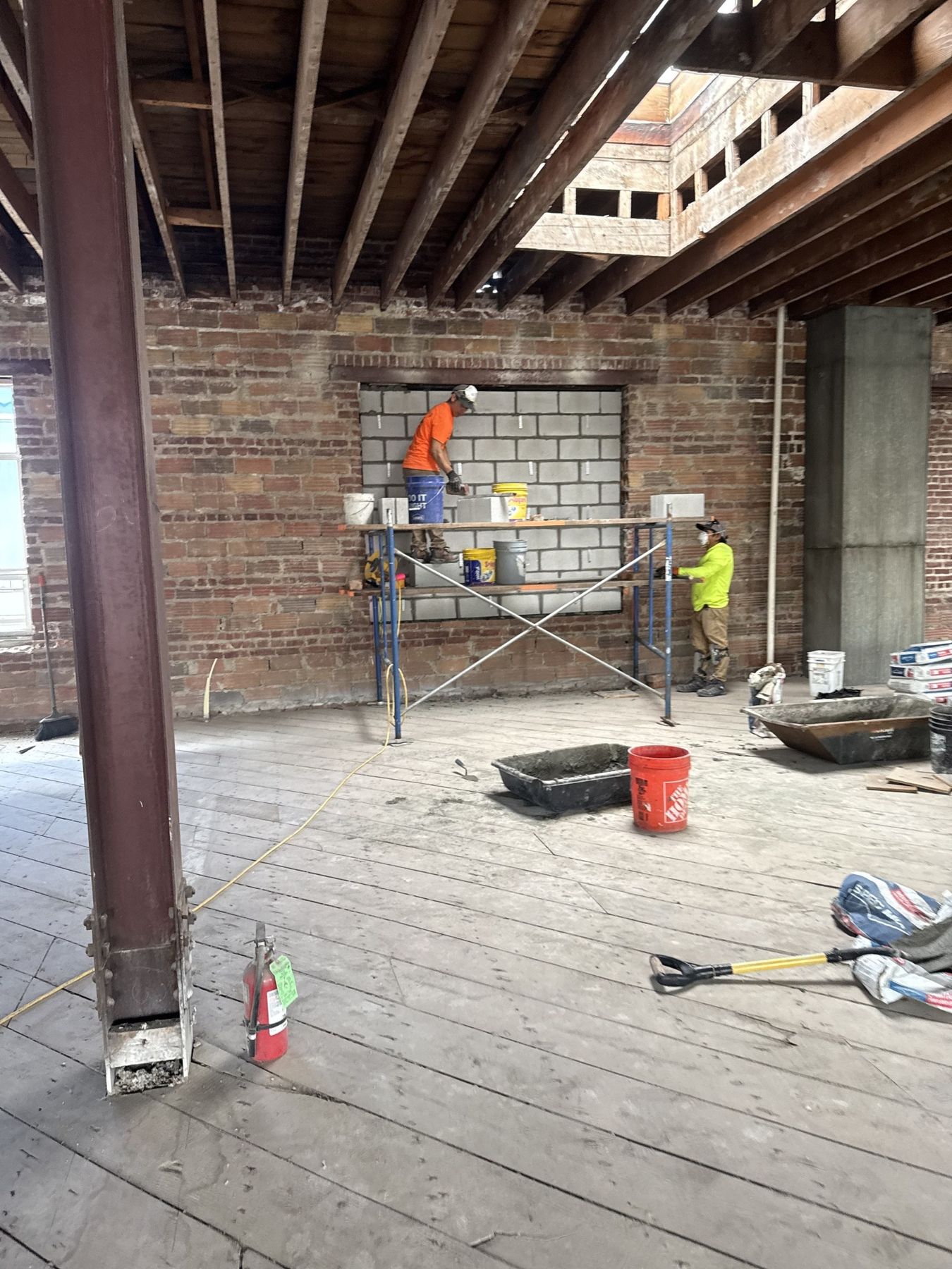 Yarussi crew on interior scaffolding building a block infill wall within a large brick opening