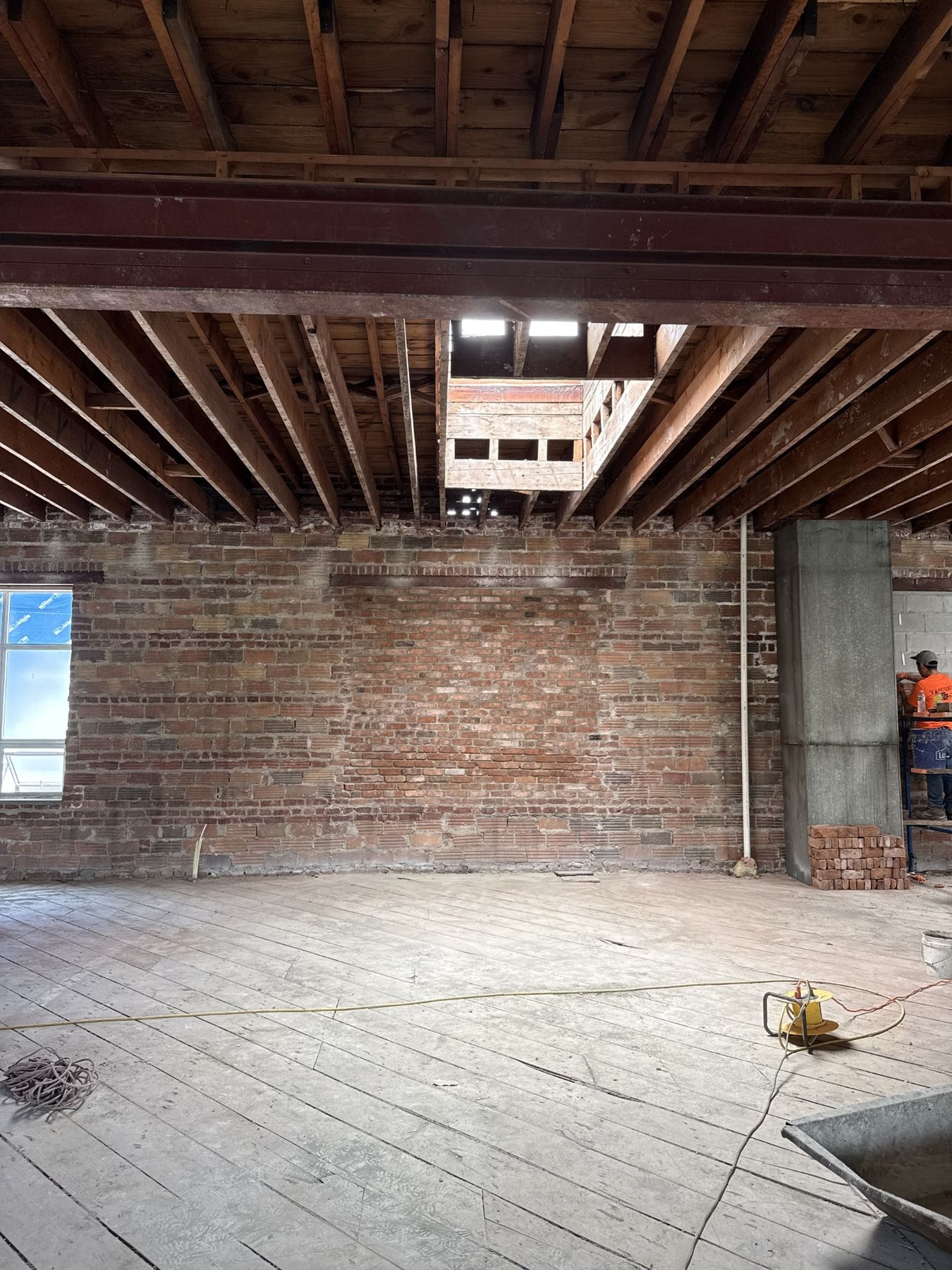 Interior exposed red brick wall and timber ceiling beams inside a building under restoration