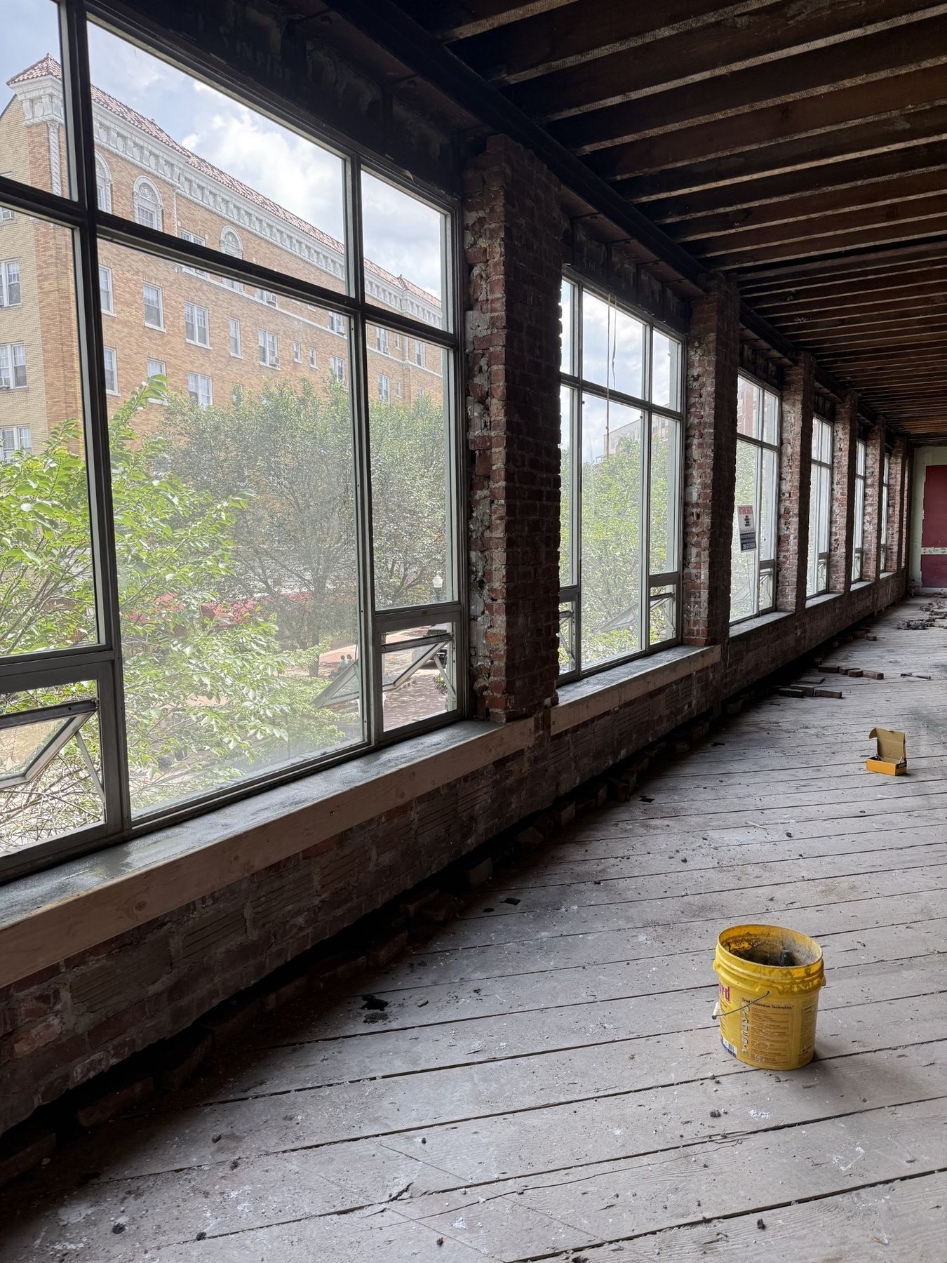 Long interior row of tall windows separated by restored brick piers in a mill conversion