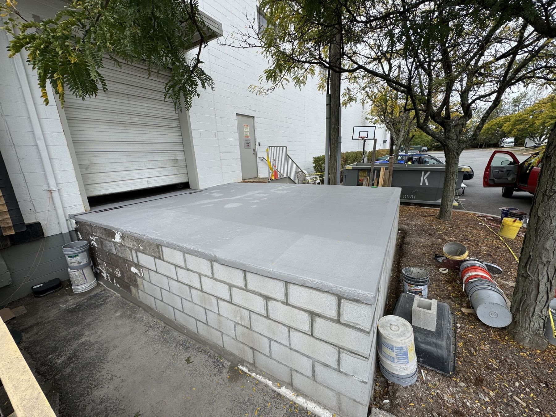 Freshly applied grey waterproof coating across a concrete loading dock platform at an industrial building