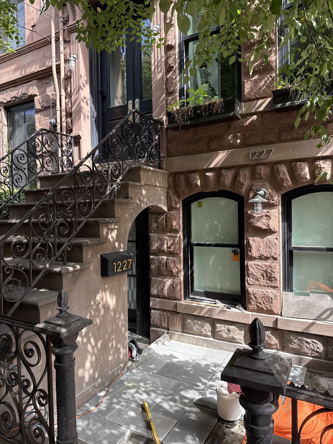 Restored brownstone stoop with rebuilt stone treads and ornate black wrought iron railings